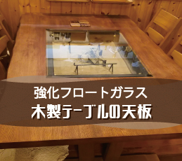 木のぬくもりを感じるテーブルの上にガラスを置かれたお客様（岐阜県